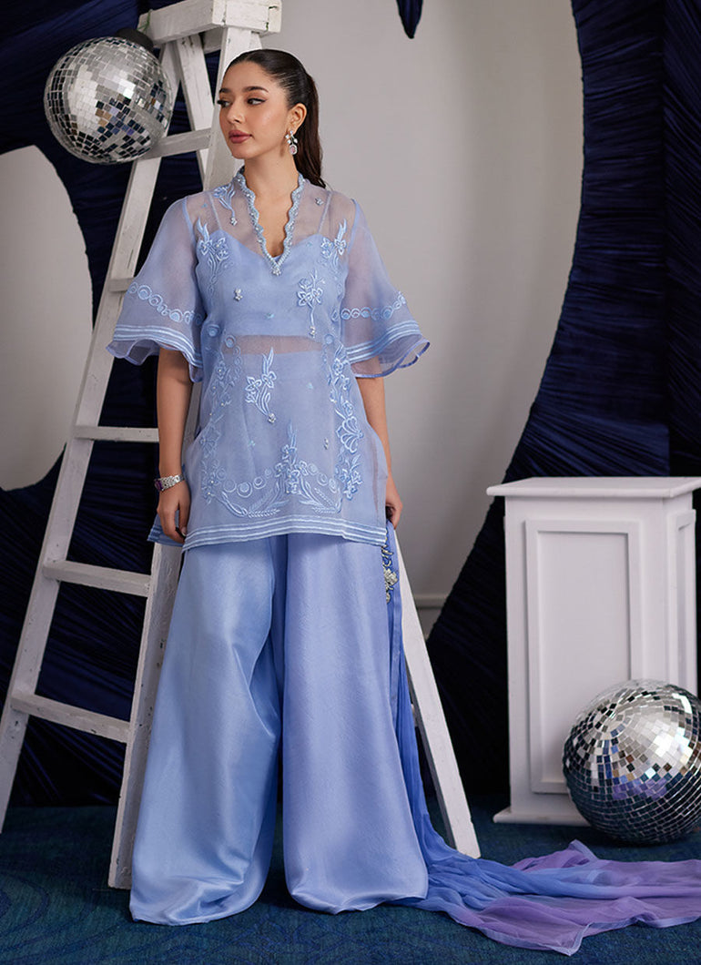 Contemporary cool yet effortlessly glam, the Cassie ensemble is going to be the trump card you need to elevate your style game!! The thigh skimming top, cut from diaphanous organza is adorned with tonal silk thread work, further uplifted with shimmering sequins and dreamy pearls. The eye-catching statement sleeves, make this an absolute must have! The organza shirt is layered over an impeccably tailored bustier and wide leg pants. The dip dyed medium silk dupatta, completes the ensemble with stunning flair.
